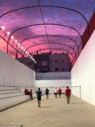 Actividad deportiva en el Trinquete José María Veguer con iluminación de colores y jugadores en acción