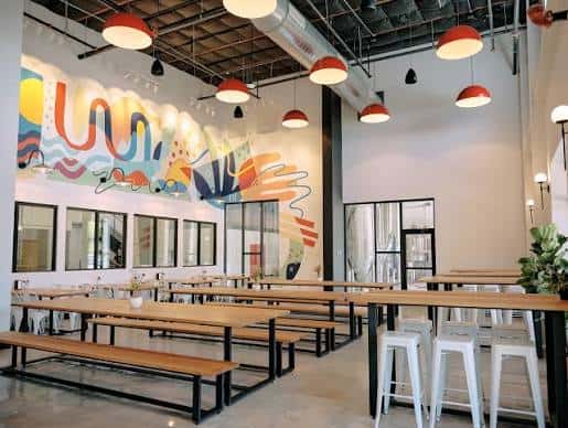 Interior del taproom con mesas largas y mural colorido