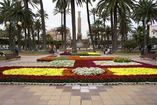 Plaza de España con jardín floral y monumentos en primer plano