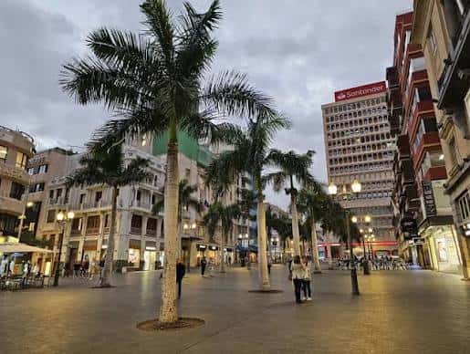 Plaza de la Candelaria al atardecer con iluminación urbana y personas caminando entre las palmeras