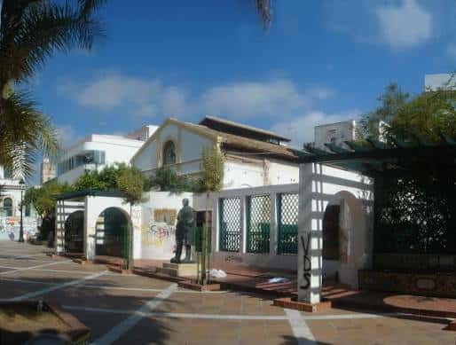 Monumento a Don Pedro Muñoz Seca en la plaza con arquitectura tradicional