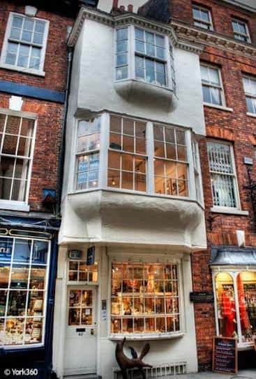 Fachada histórica de la Pyramid Gallery en York con ventanas curvas y escaparate iluminado