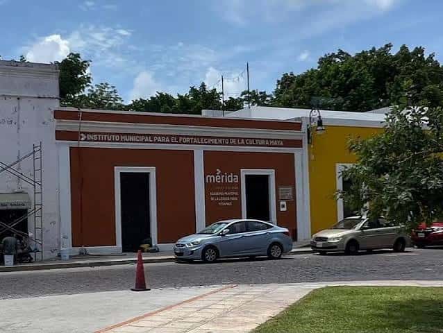 Vista exterior del edificio del instituto con vehículos estacionados frente a la entrada principal