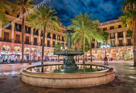 Plaza Real iluminada por la noche con la fuente central como foco