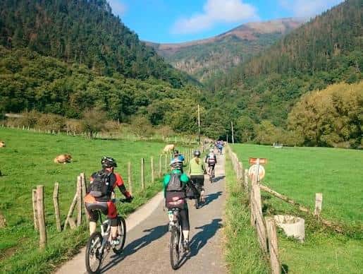 Ciclistas disfrutando de la Vía Verde del Bidasoa en un paisaje verde y montañoso