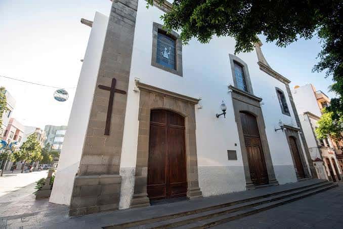 Vista lateral de la iglesia mostrando la cruz y las ventanas con vitrales