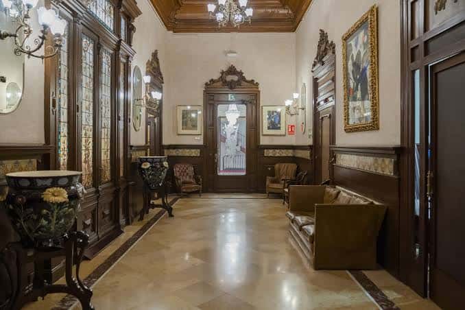 Pasillo principal con mobiliario clásico, espejos y obras de arte enmarcadas