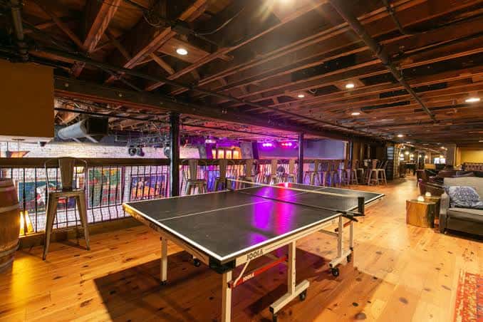 Sala de eventos con mesa de ping pong y barra en el fondo