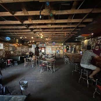 Interior del bar con techo de vigas de madera, mesas y barra