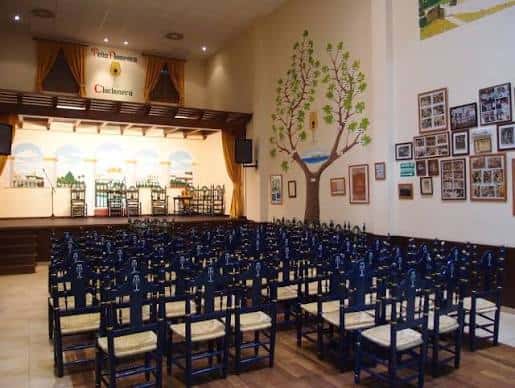 Interior de la Peña Flamenca Chiclanera con escenario y butacas azules