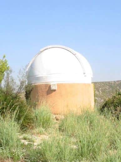 Primer plano de la cúpula del observatorio sobre el cuerpo cilíndrico de adobe, con cielo despejado