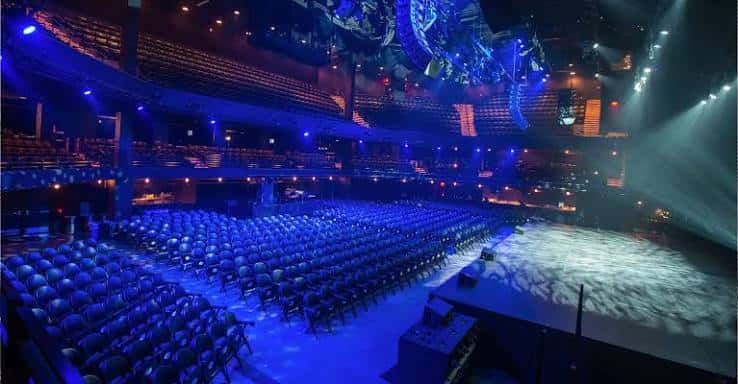 Vista panorámica del interior del auditorio con butacas y escenario bajo iluminación azul
