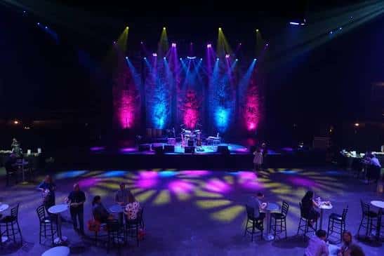 Escenario con iluminación de colores y mesas de invitados en primer plano