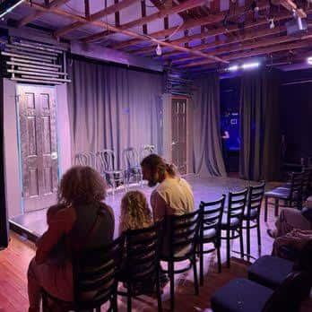 Interior del teatro con público sentado frente al escenario