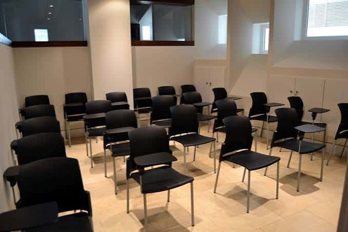 Sala de conferencias con sillas negras dispuestas para evento