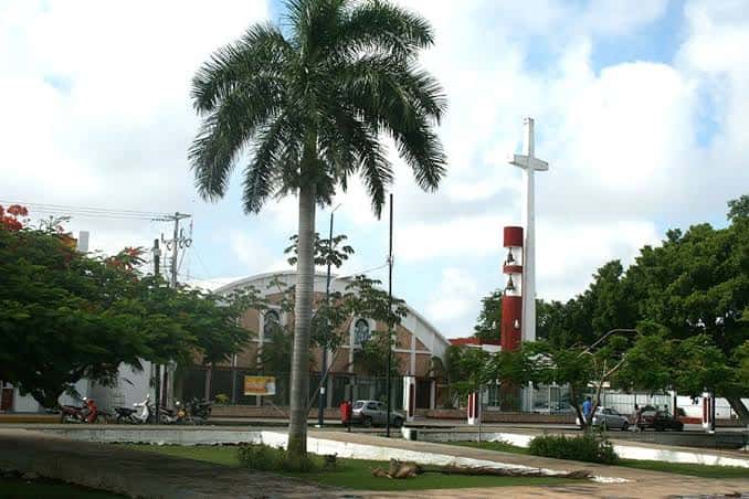 Fachada de la iglesia del parque con su característica torre roja y cruz blanca