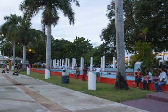 Área de descanso del parque con columnas blancas y personas disfrutando del ambiente familiar