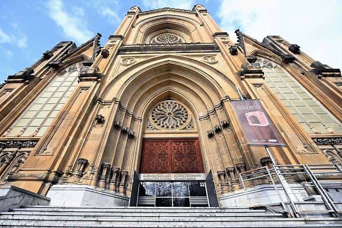 Entrada principal del edificio con cartel de exposición y detalles arquitectónicos góticos