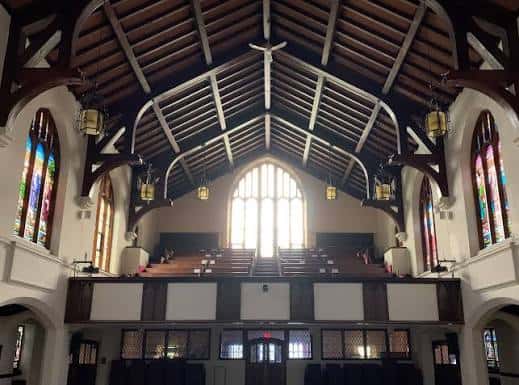 Interior de la iglesia con techo de vigas de madera y ventanales de vitrales