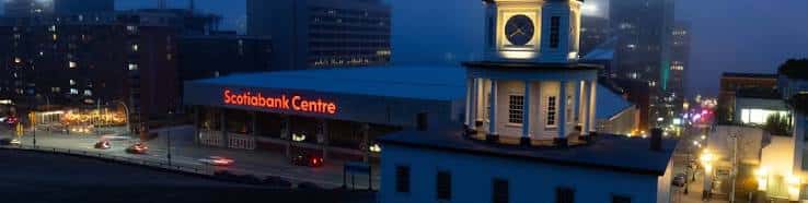 Vista nocturna del Scotiabank Centre con iluminación exterior y el reloj histórico adyacente