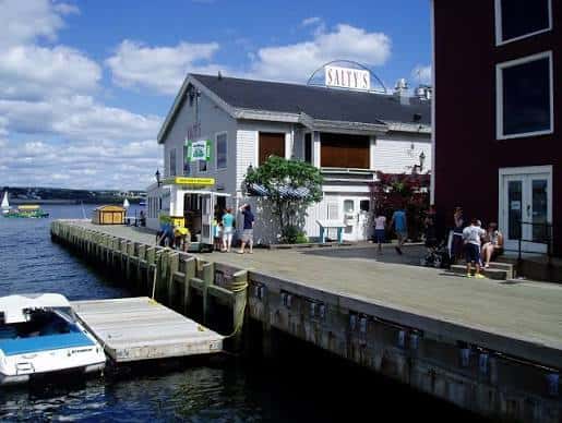 Edificio junto al muelle con personas sentadas y barcos atracados