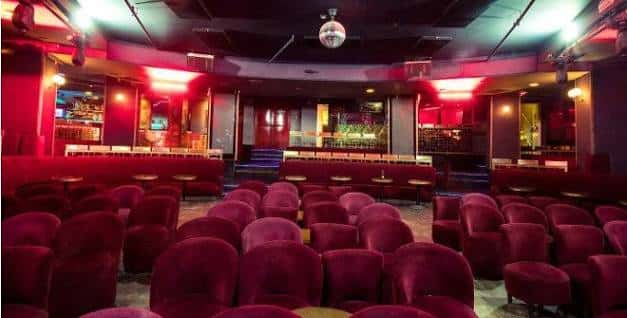 Sala de eventos con butacas, barra y iluminación ambiental