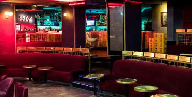 Zona de lounge con sofás rojos y barra iluminada