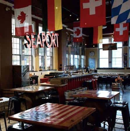 Interior del bar Seaport con mesas y banderas internacionales colgando del techo