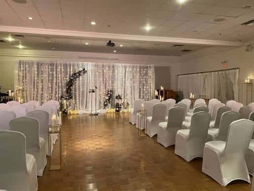 Sala de eventos preparada para una boda con sillas blancas y cortinas decorativas