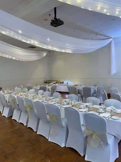 Sala de banquetes decorada con mesas redondas y mantelería blanca