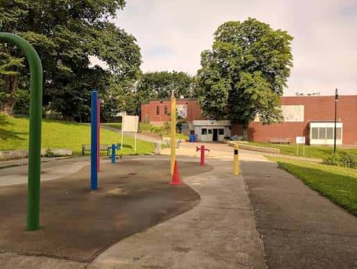 Área de juegos al aire libre frente al centro comunitario con equipamiento deportivo colorido