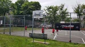 Cancha de baloncesto al aire libre con personas jugando, ubicada en las instalaciones del centro