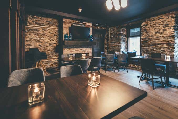 Sala acogedora con paredes de piedra y mesas con velas, ideal para eventos íntimos