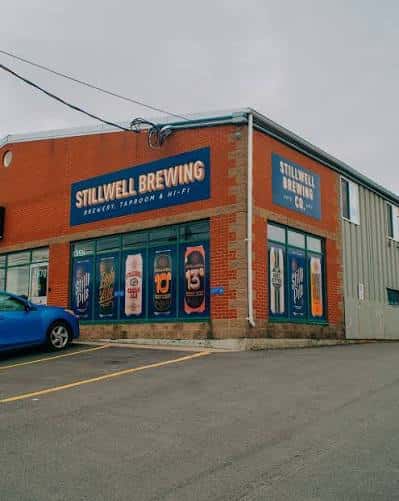 Vista amplia del edificio de Stillwell Brewing desde la calle con estacionamiento