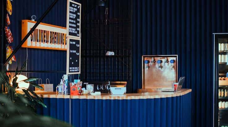 Interior del bar con mostrador de madera, grifos de cerveza y decoración industrial