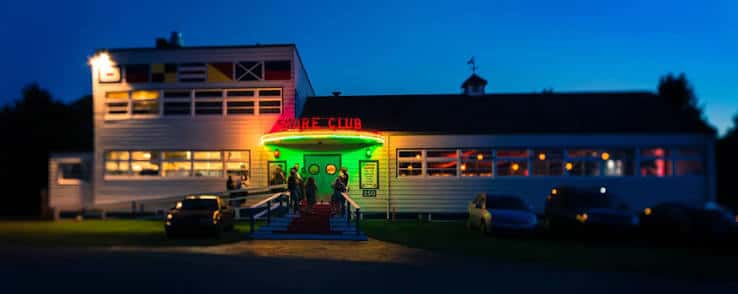 Fachada del Shore Club iluminada por la noche con letrero neón y entrada activa