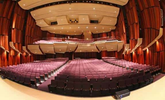Interior del auditorio principal con butacas rojas y diseño acústico curvo