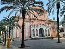 Plaza de les Neus al atardecer con la fachada de la iglesia iluminada