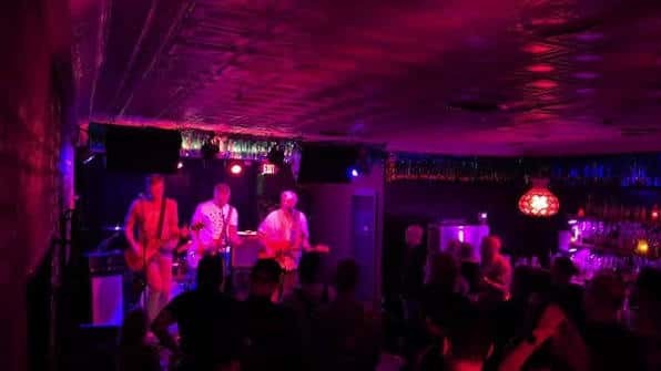Escenario con banda tocando en ambiente festivo con luces de colores