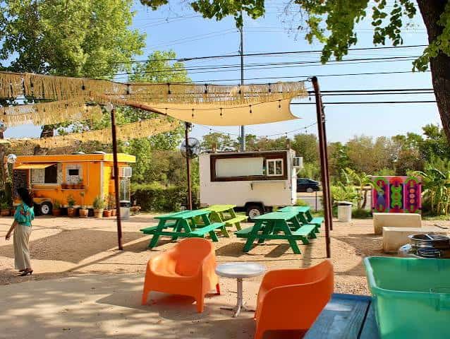 Área al aire libre con mesas de picnic y caravanas de comida