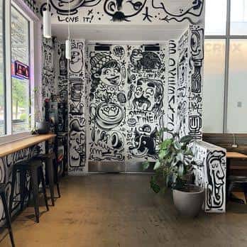 Detalle de la pared con ilustraciones artísticas y zona de plantas