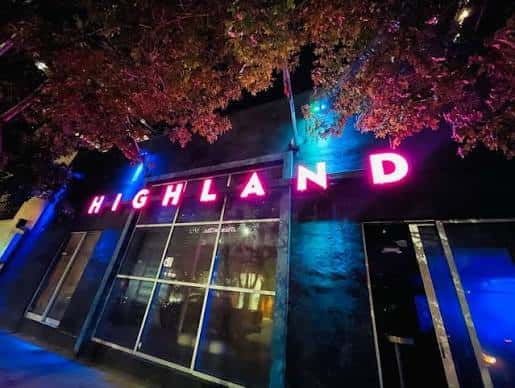 Vista nocturna de la fachada del Highland Lounge con su distintivo letrero de neón rosa