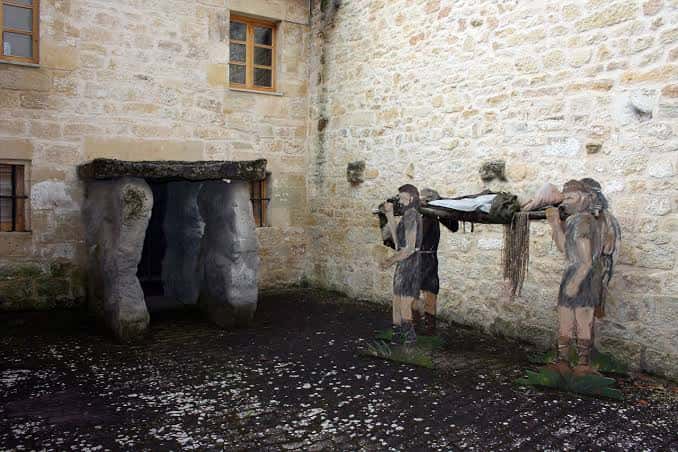 Recreación de un dolmen con figuras de neolíticos en el patio del centro de interpretación