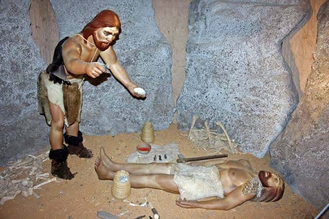 Escena expositiva con maniquíes mostrando rituales funerarios en un entorno de cueva