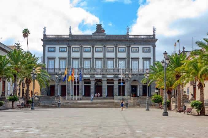 Plaza principal frente al ayuntamiento con banderas y cielo azul