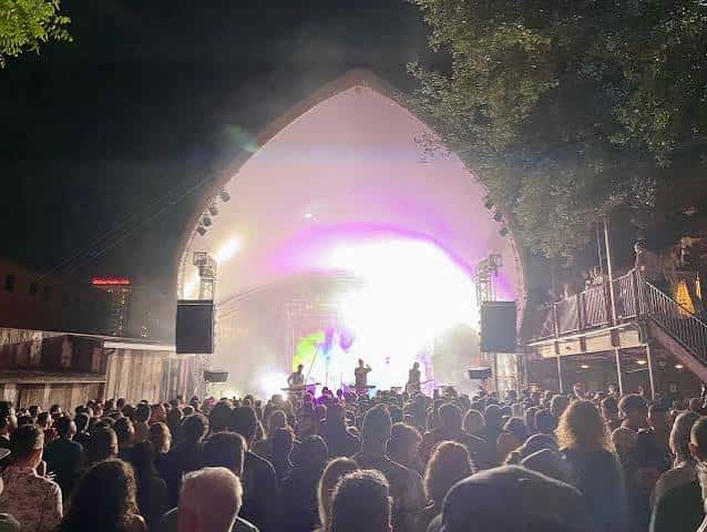 Concierto nocturno en el escenario al aire libre con público asistiendo