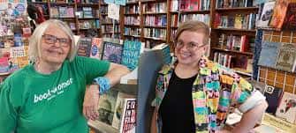 Dos personas sonrientes en el interior de la librería rodeadas de estanterías de libros