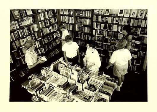Vista en blanco y negro del interior de la librería con clientes y empleados entre las estanterías
