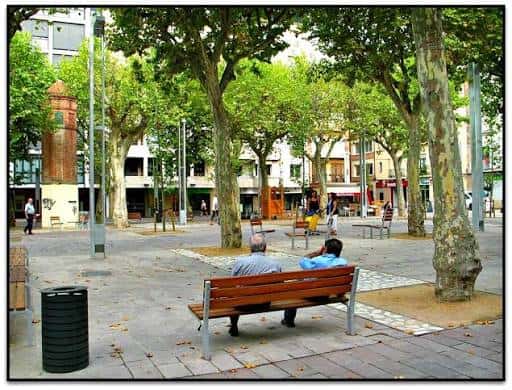 Vista general de la Plaça de la Corona con árboles y bancos