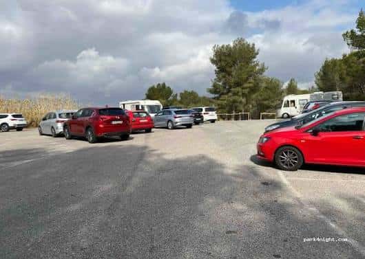 Parking del Pont del Diable con varios coches y autocaravanas bajo cielo nublado